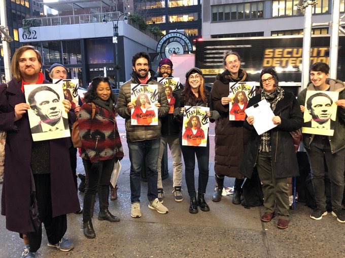 an image of nine activists holding posters of representing incarcerated survivors of gender violence, and Cuomo's face as he is responsible for not freeing them.